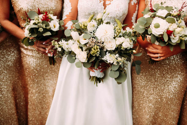 Bride holding bouquet, bridesmaids in sparkly dresses