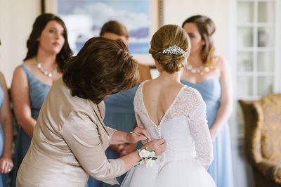 Mother of the bride assisting with the bridal gown